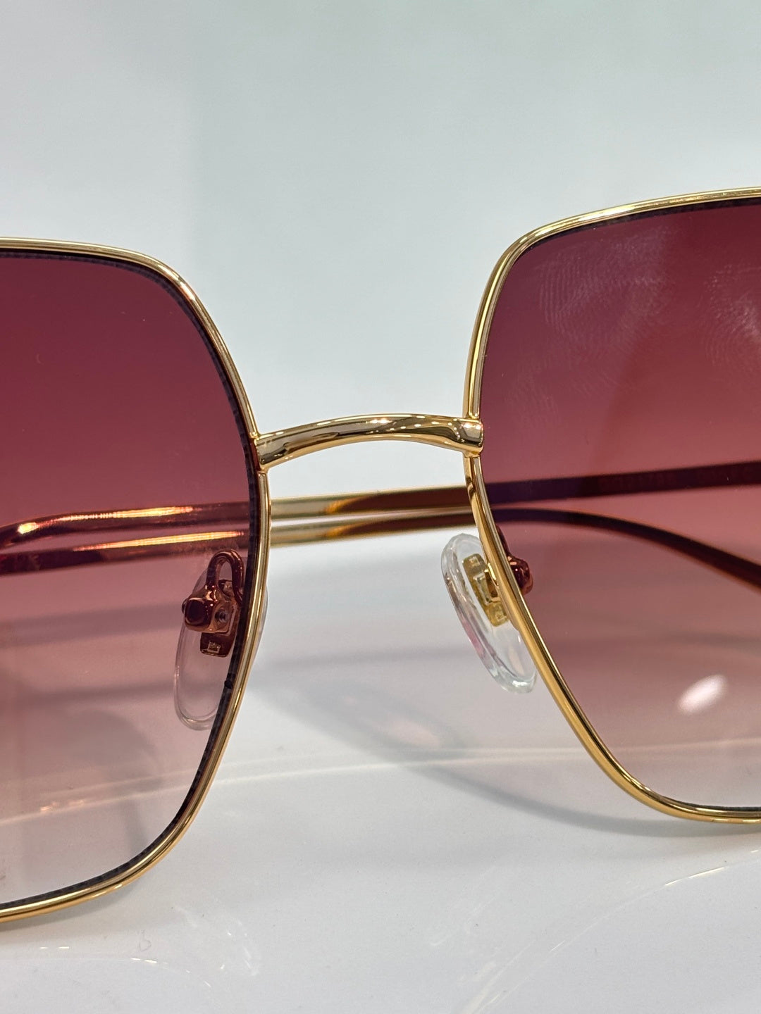 Front view sunglasses with gold-tone frames and maroon gradient lenses