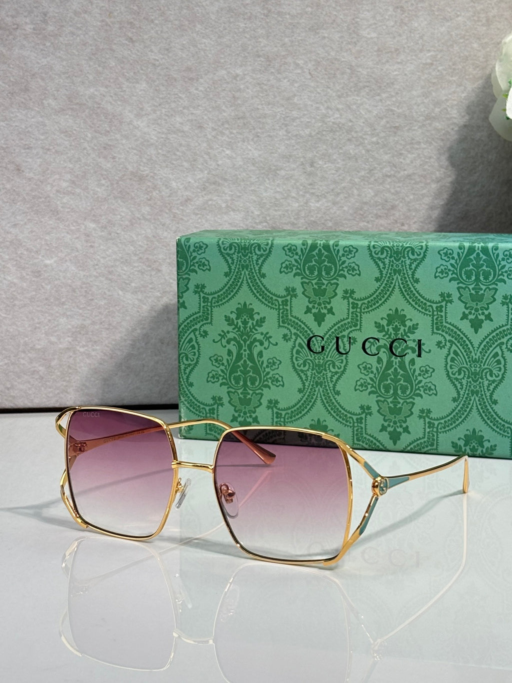Square sunglasses with gold-tone frames and light pink gradient lenses