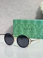 Round eyeglasses with gold metal frames and dark, smoky tinted lenses