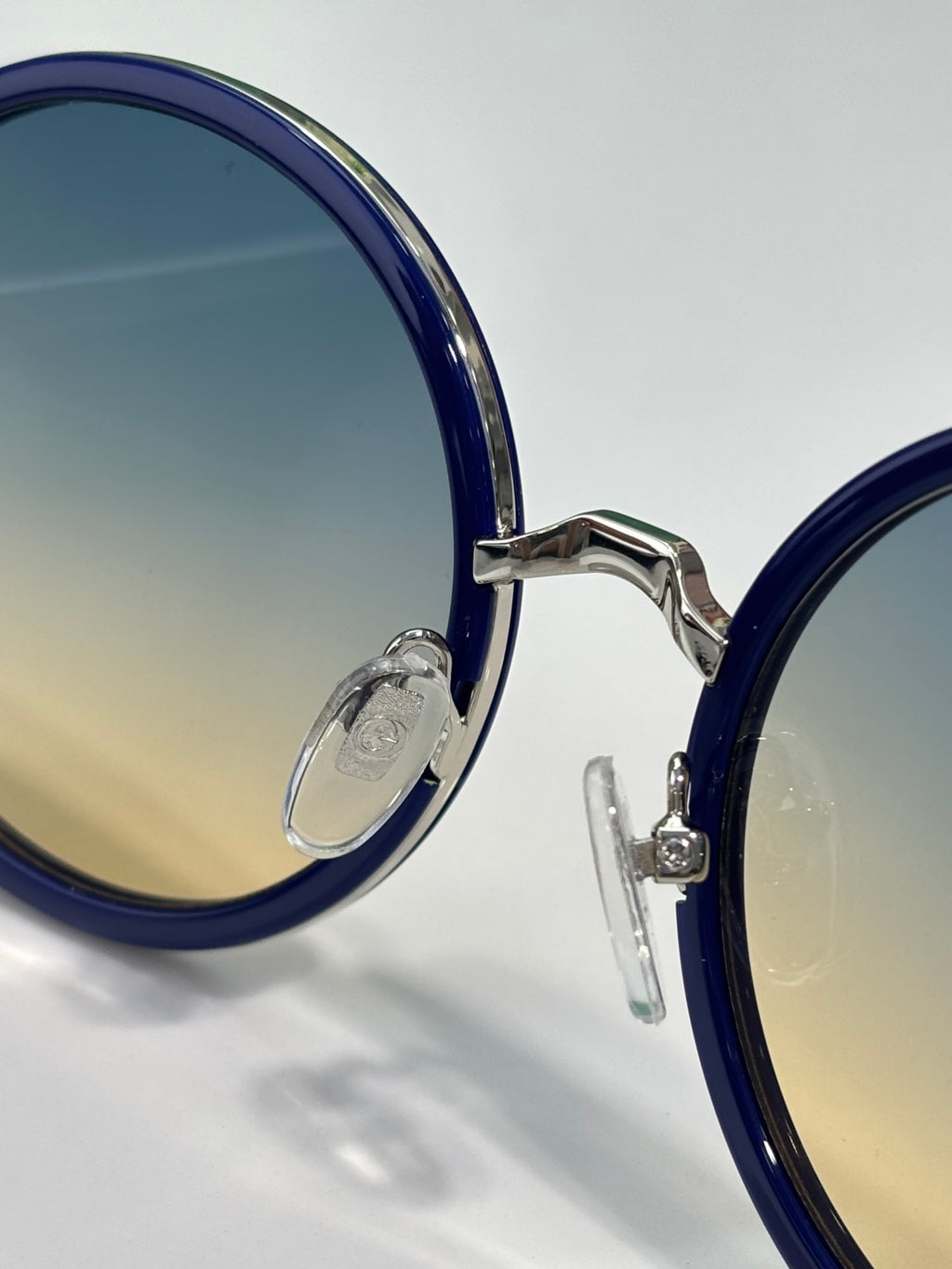 Round eyeglasses close-up: dark blue frames with silver bridge and lens edge