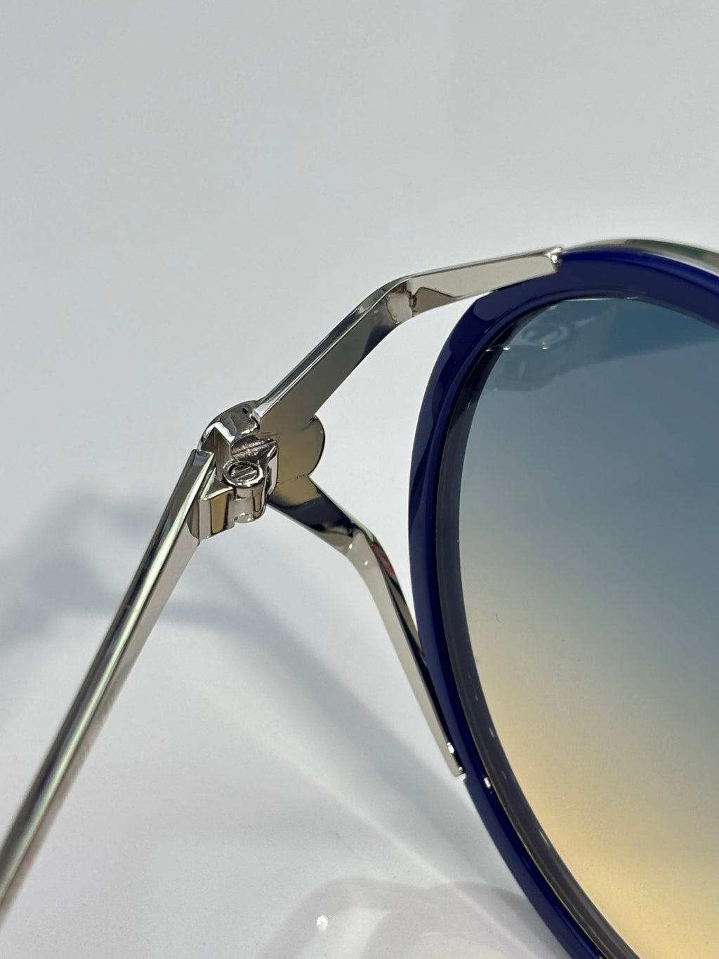 Round eyeglasses close-up: dark blue frame with silver hinge and side temple