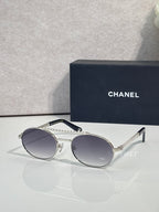 Round sunglasses with silver frame and dark tinted lenses, beaded temple detail.
