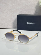 Round sunglasses with gold frame and dark tinted lenses, beaded temple detail.