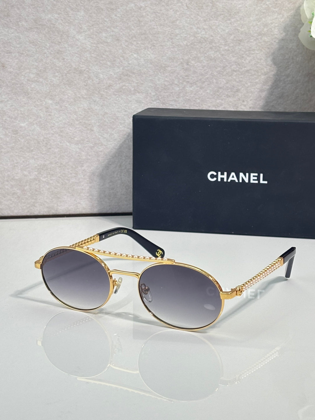 Round sunglasses with gold frame and dark tinted lenses, beaded temple detail.