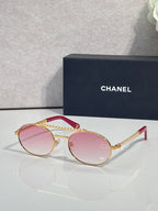 Round sunglasses with gold frame and pink tinted lenses, beaded temple detail.
