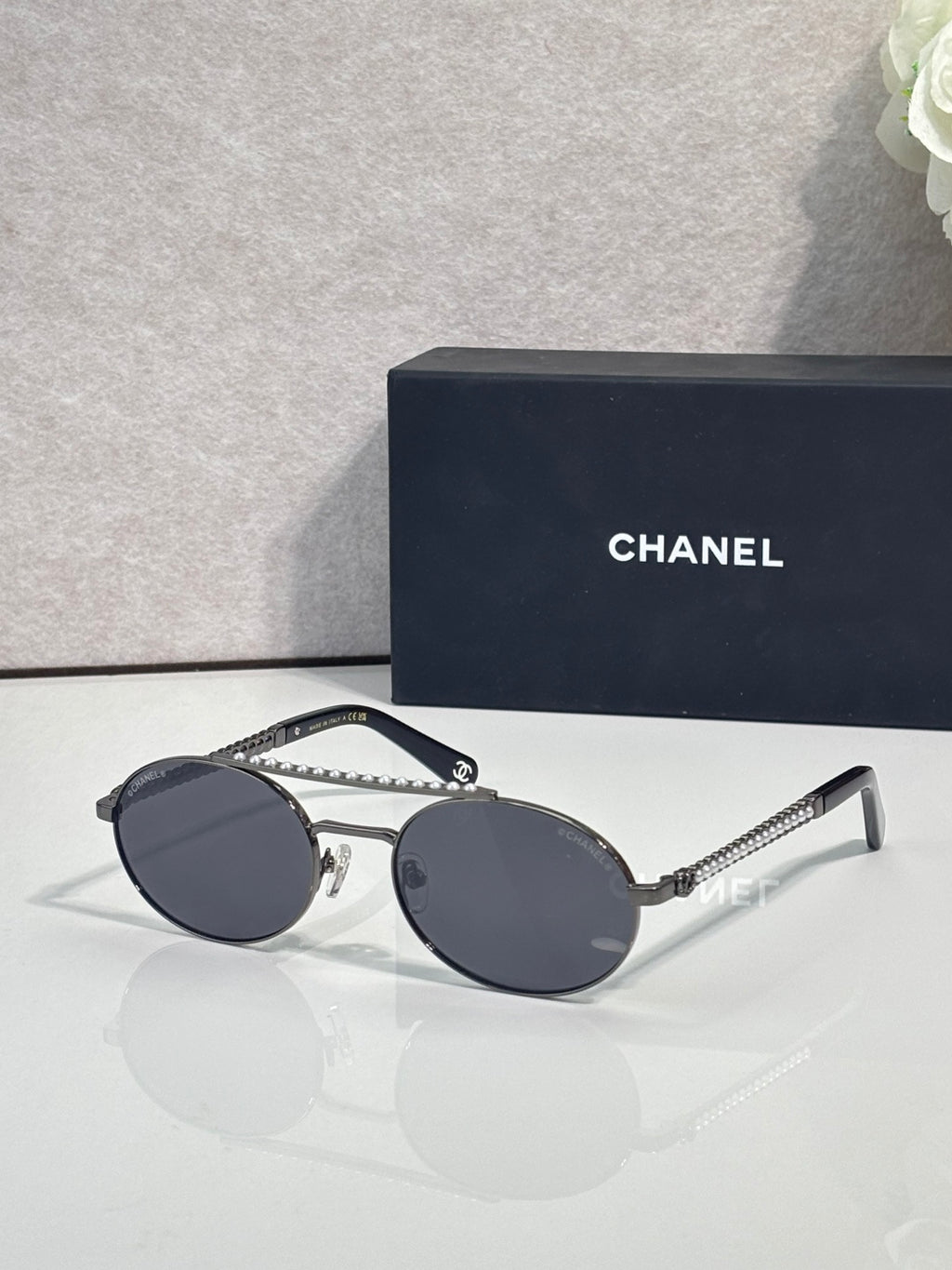 Round sunglasses with dark frame and dark tinted lenses, beaded temple detail.