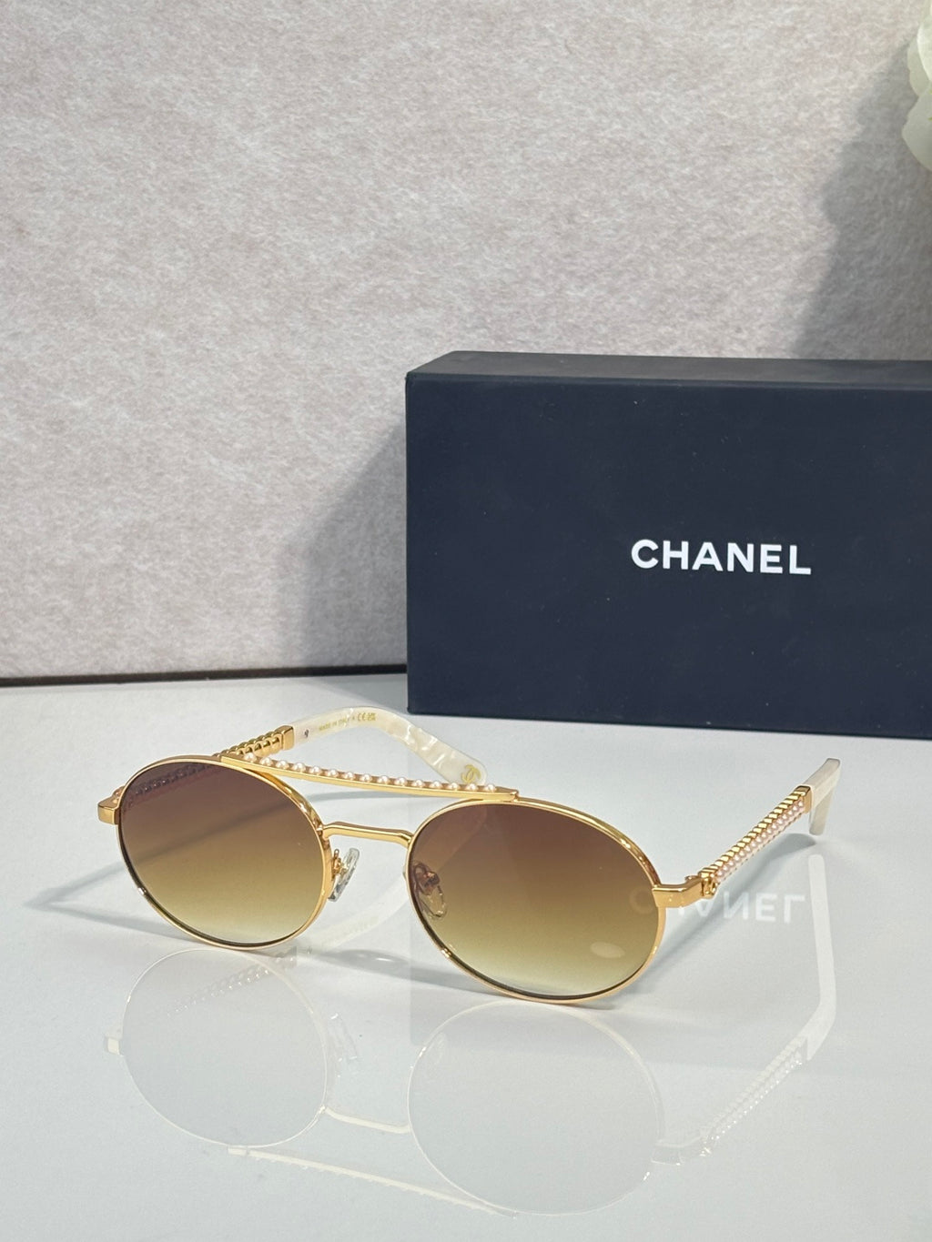 Round sunglasses with gold frame and amber tinted lenses, beaded temple detail.