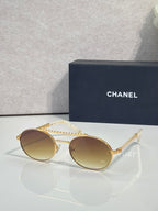 Round sunglasses with gold frame and amber tinted lenses, beaded temple detail.