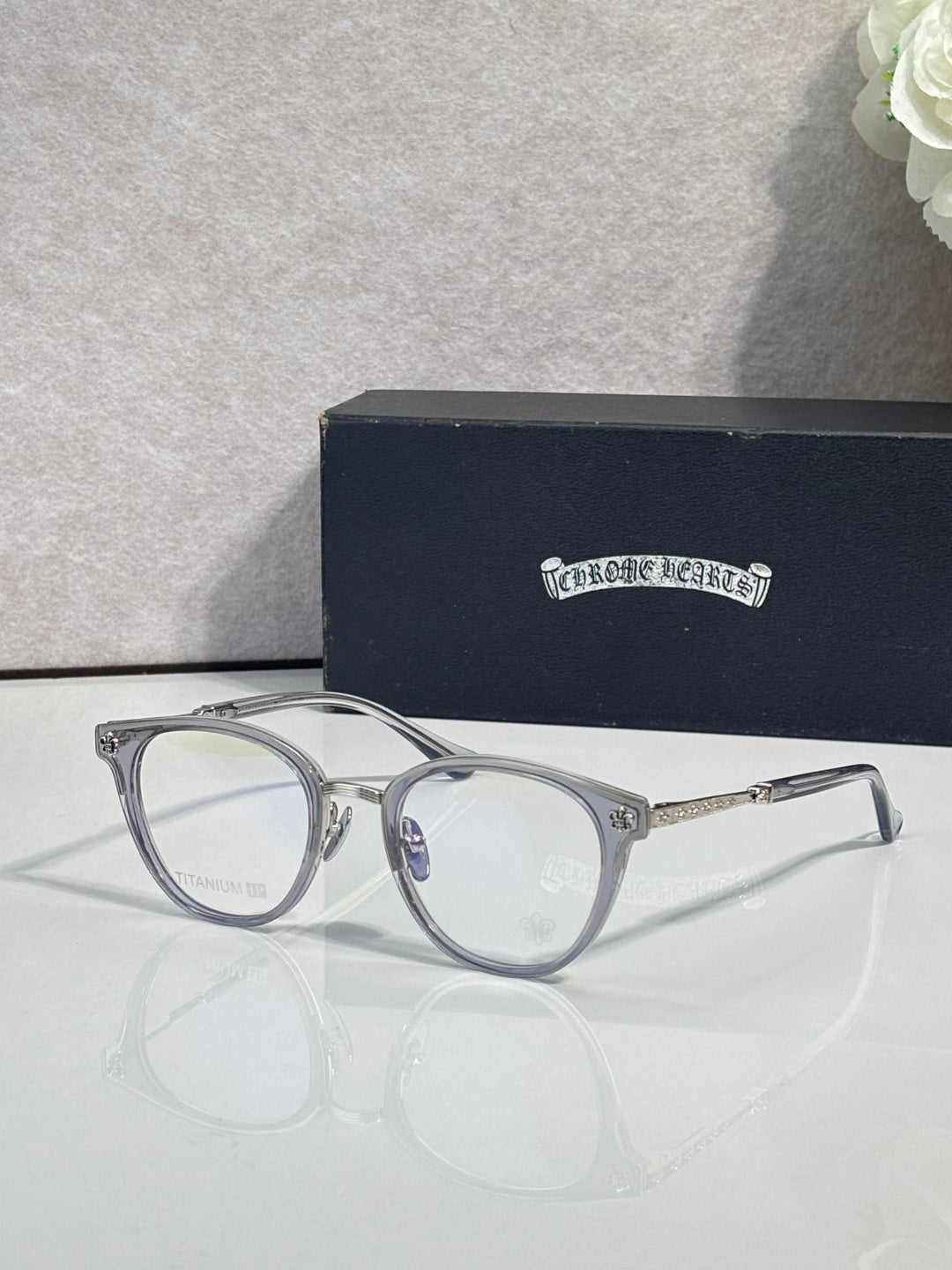 Silver round eyeglasses with clear lenses and decorative hinges