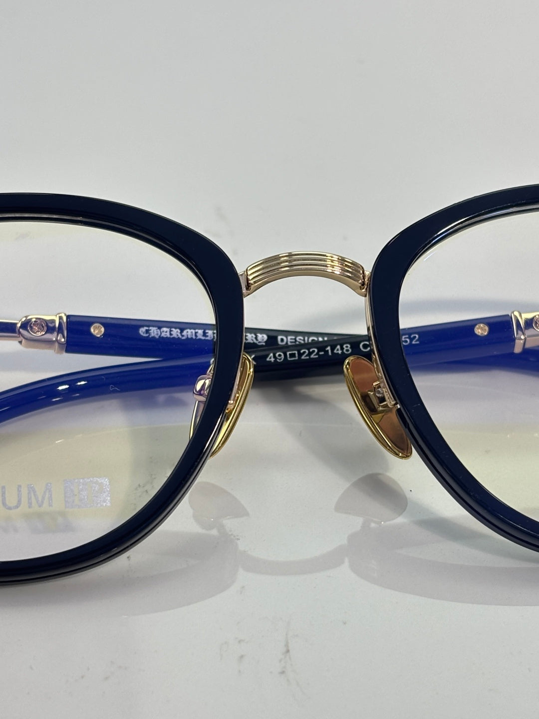 Navy eyeglasses with gold bridge, clear lenses, and side markings