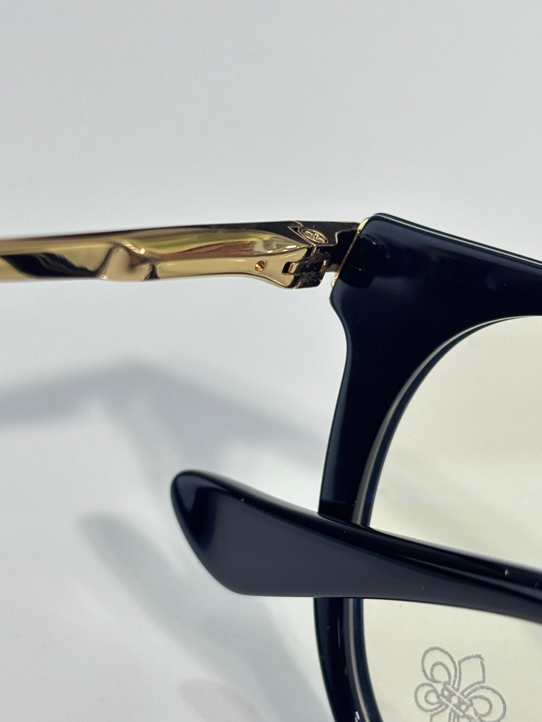 Navy eyeglass arm with gold hinge detail and clear lens