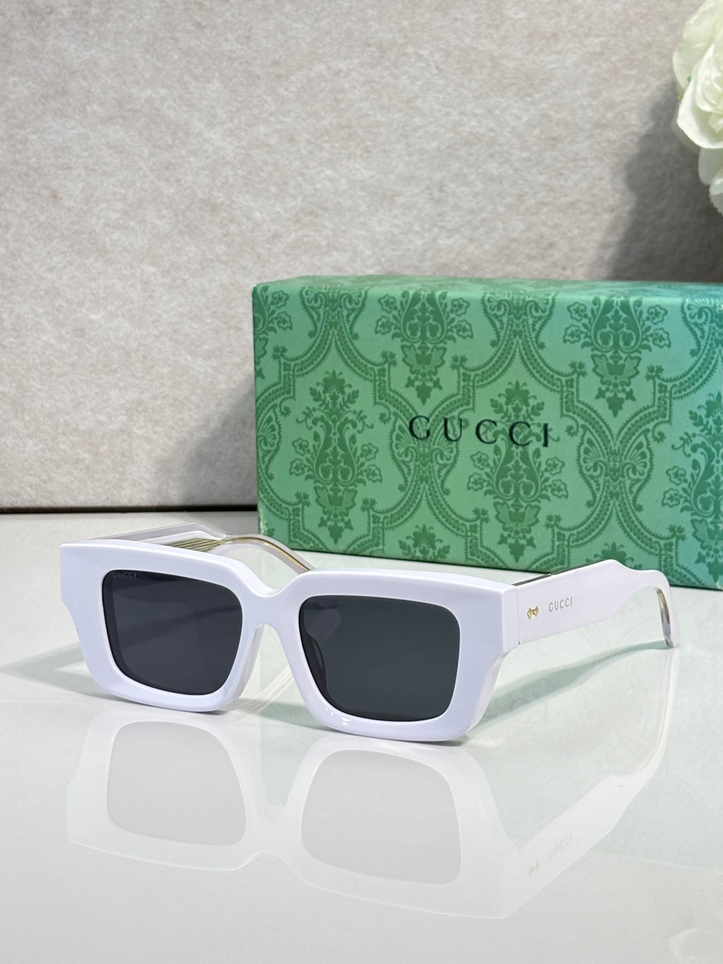 White rectangular sunglasses with dark lenses and Gucci logo on side arms.