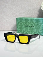 Black rectangular sunglasses with yellow lenses and Gucci logo on side arms.
