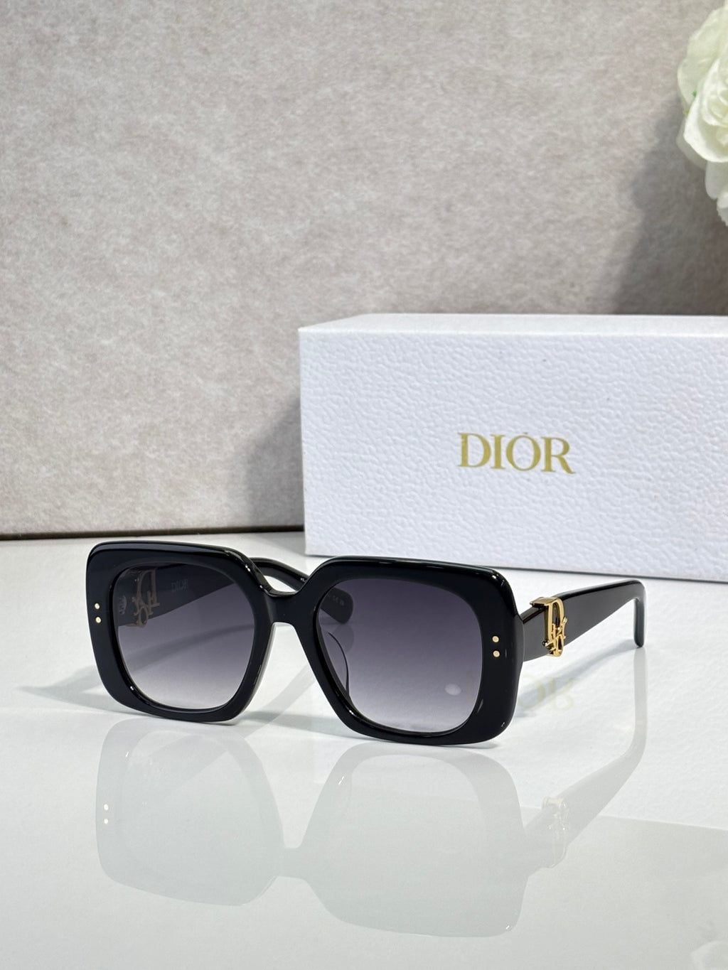 Black Dior sunglasses with square frames and gold logo hardware.
