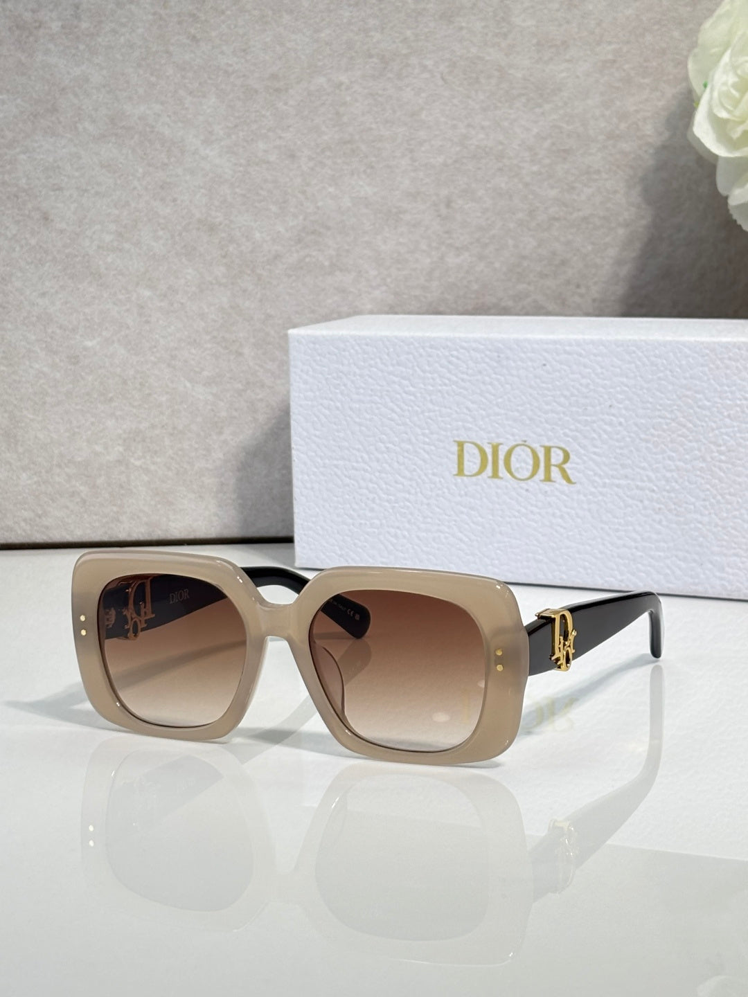 Dior sunglasses with beige square frames, brown gradient lenses, and gold logo detail