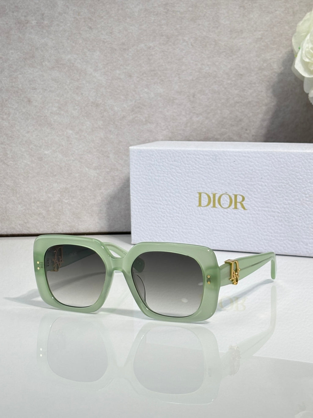 Dior sunglasses with light green frames and gray gradient lenses, gold logo hinge detail