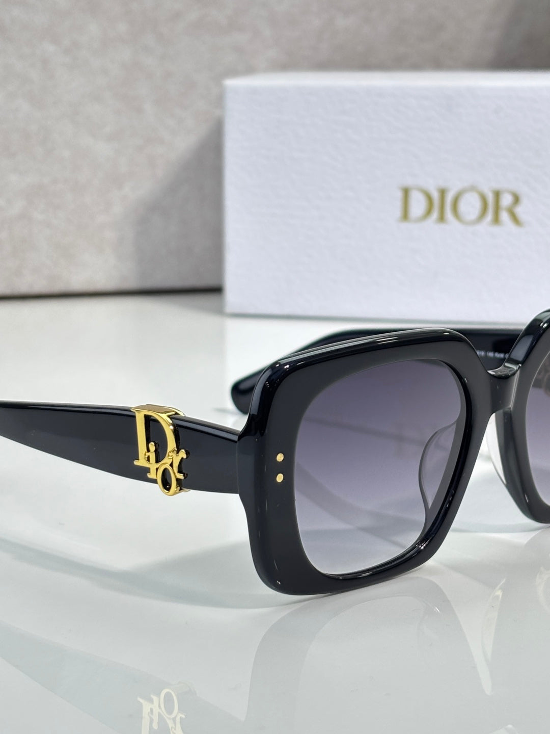 Black Dior sunglasses, side view with gold D logo on the arm.