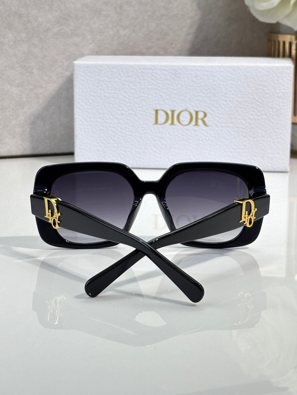 Black Dior oversized sunglasses with gold logo temples and dark lenses.