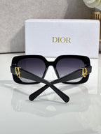 Black Dior oversized sunglasses with gold logo temples and dark lenses.