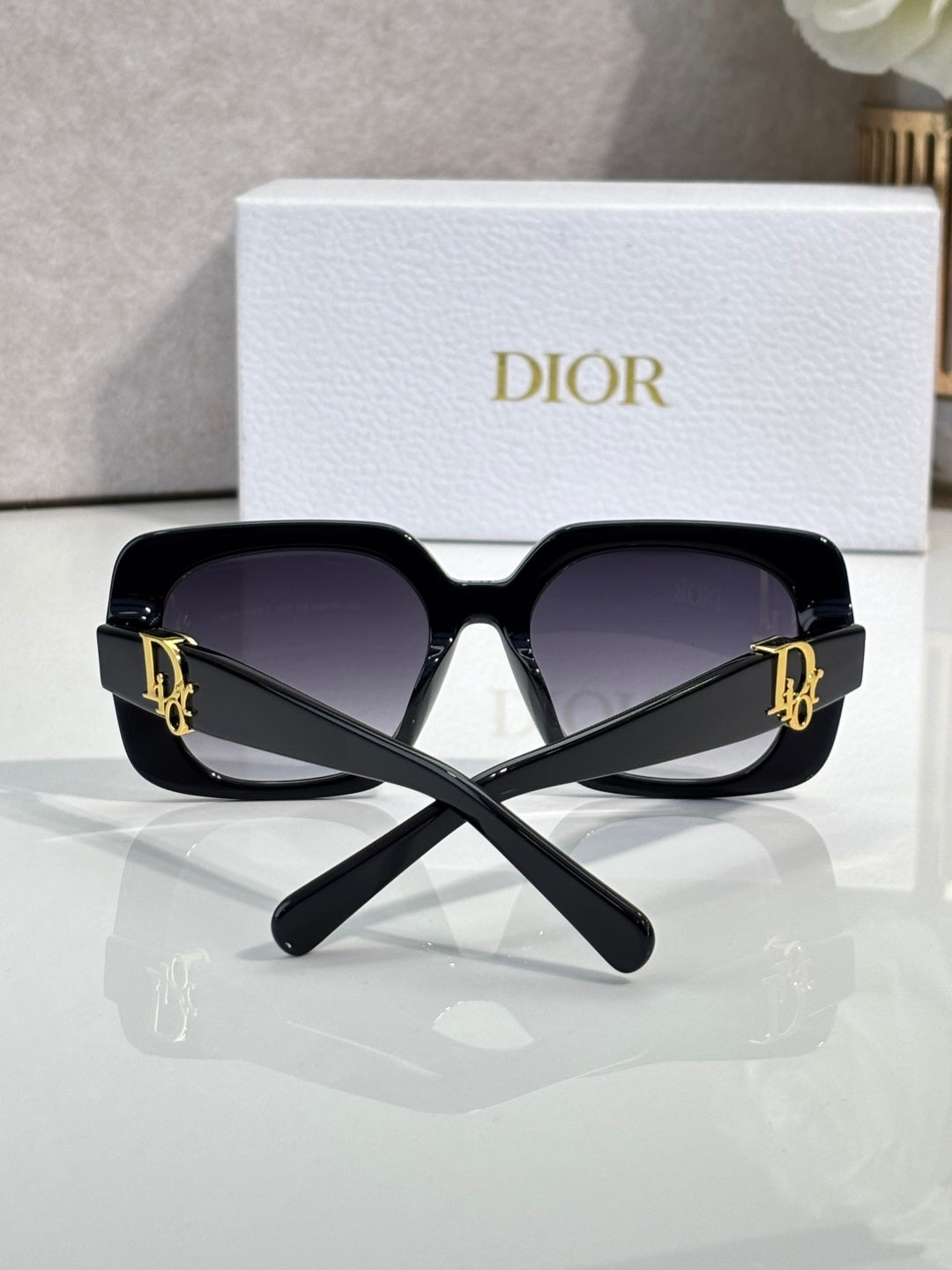 Black Dior oversized sunglasses with gold logo temples and dark lenses.