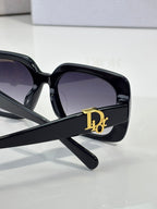 Black Dior sunglasses with gold D emblem on the temple and dark lenses.
