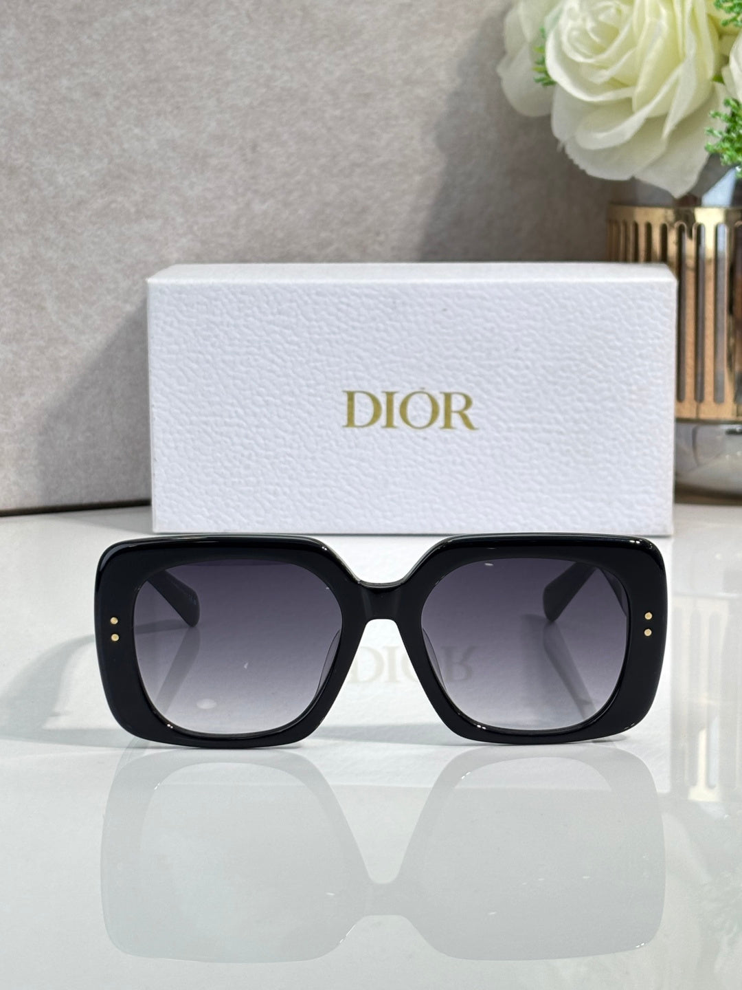 Black oversized sunglasses with gold stud details and gradient dark lenses.