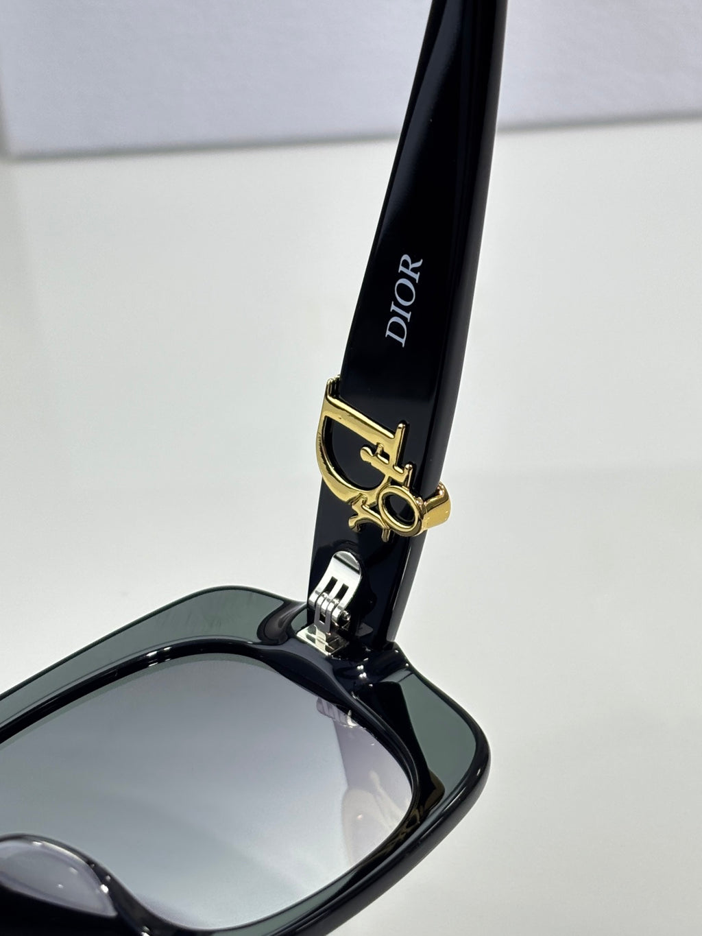 Black sunglasses arm with Dior text and gold bar logo hardware.