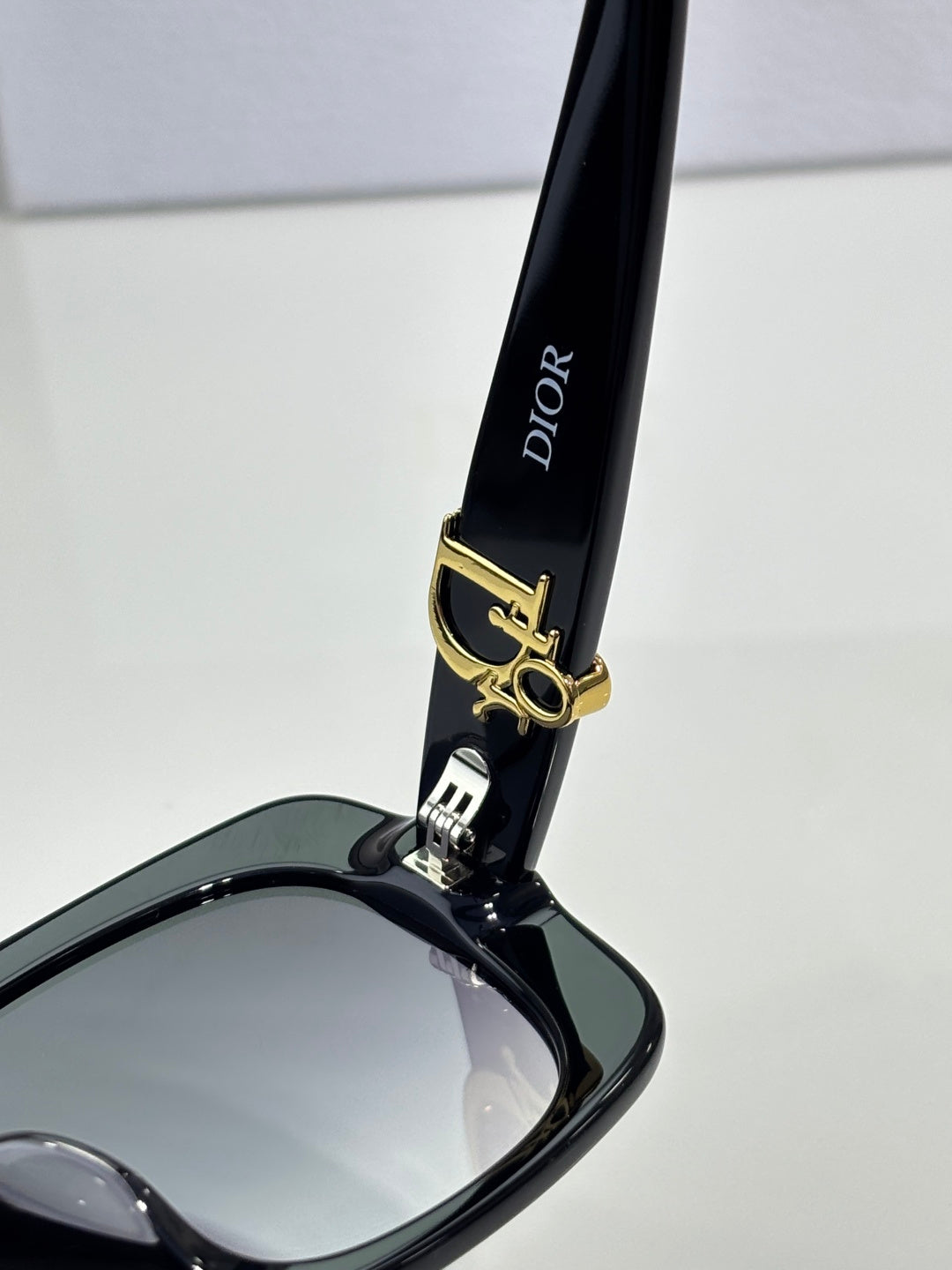 Black sunglasses arm with Dior text and gold bar logo hardware.