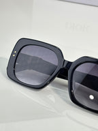 Black oversized sunglasses with dark gradient lenses and wide frame.