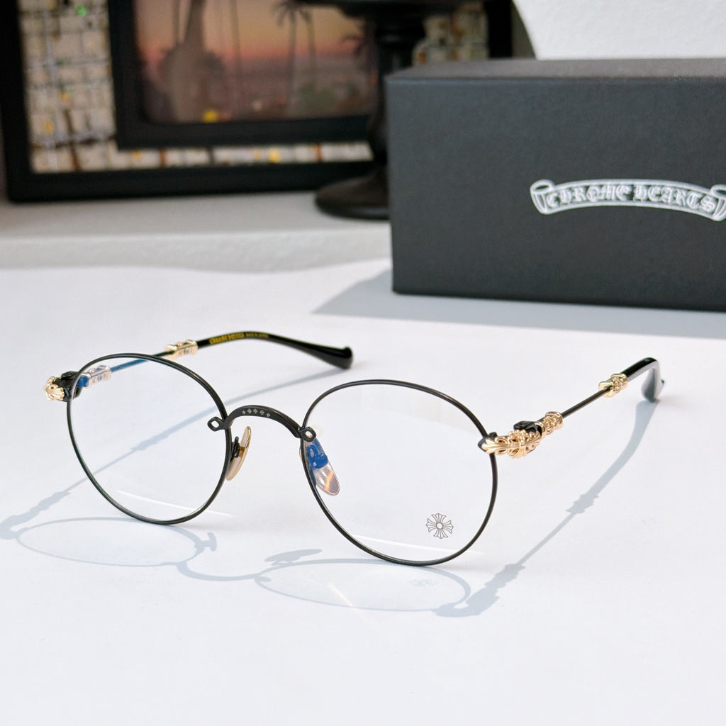 Round metal eyeglasses with clear lenses, dark frame, and gold-toned temple details