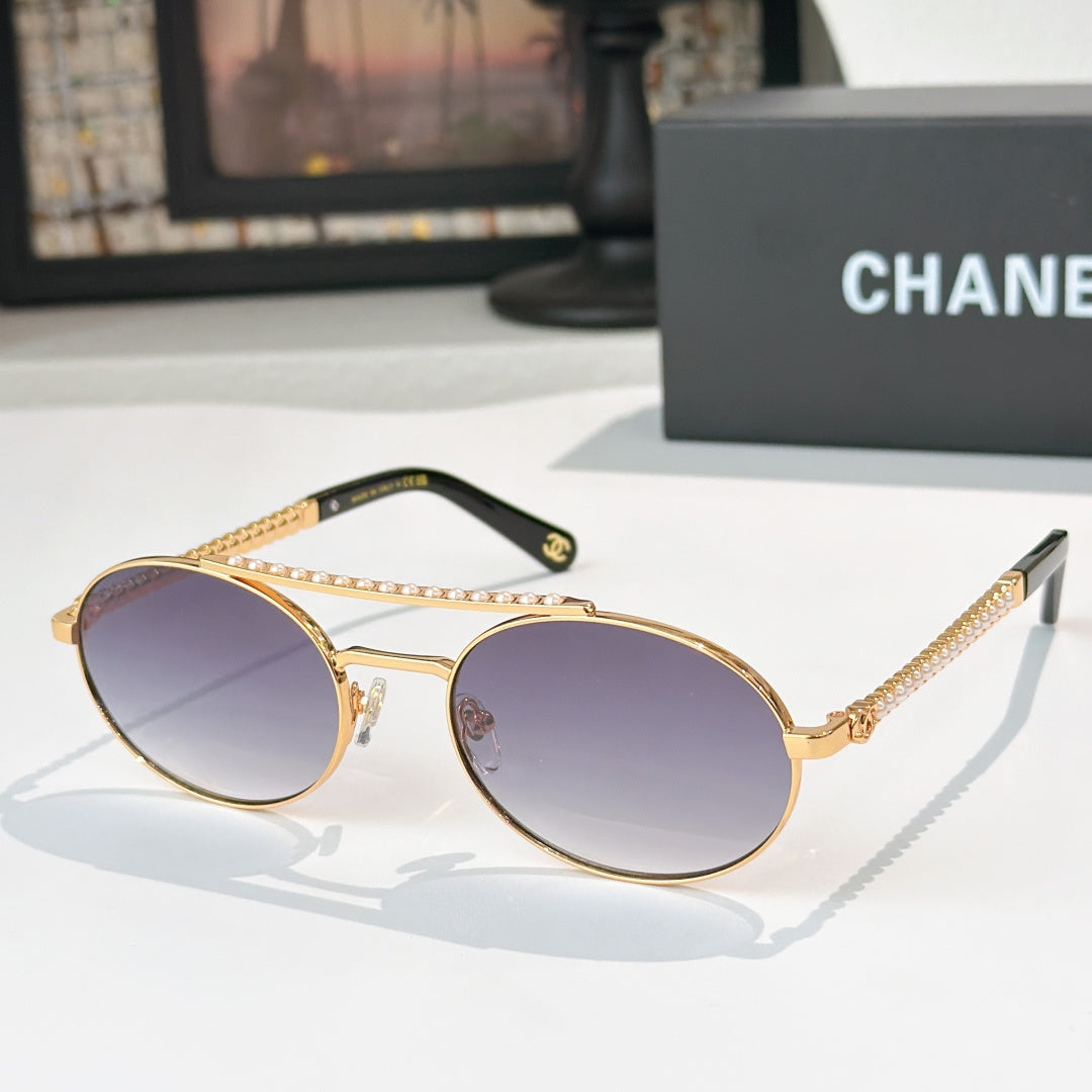 Gold-tone round sunglasses with violet tinted lenses and rhinestone chain temple detail
