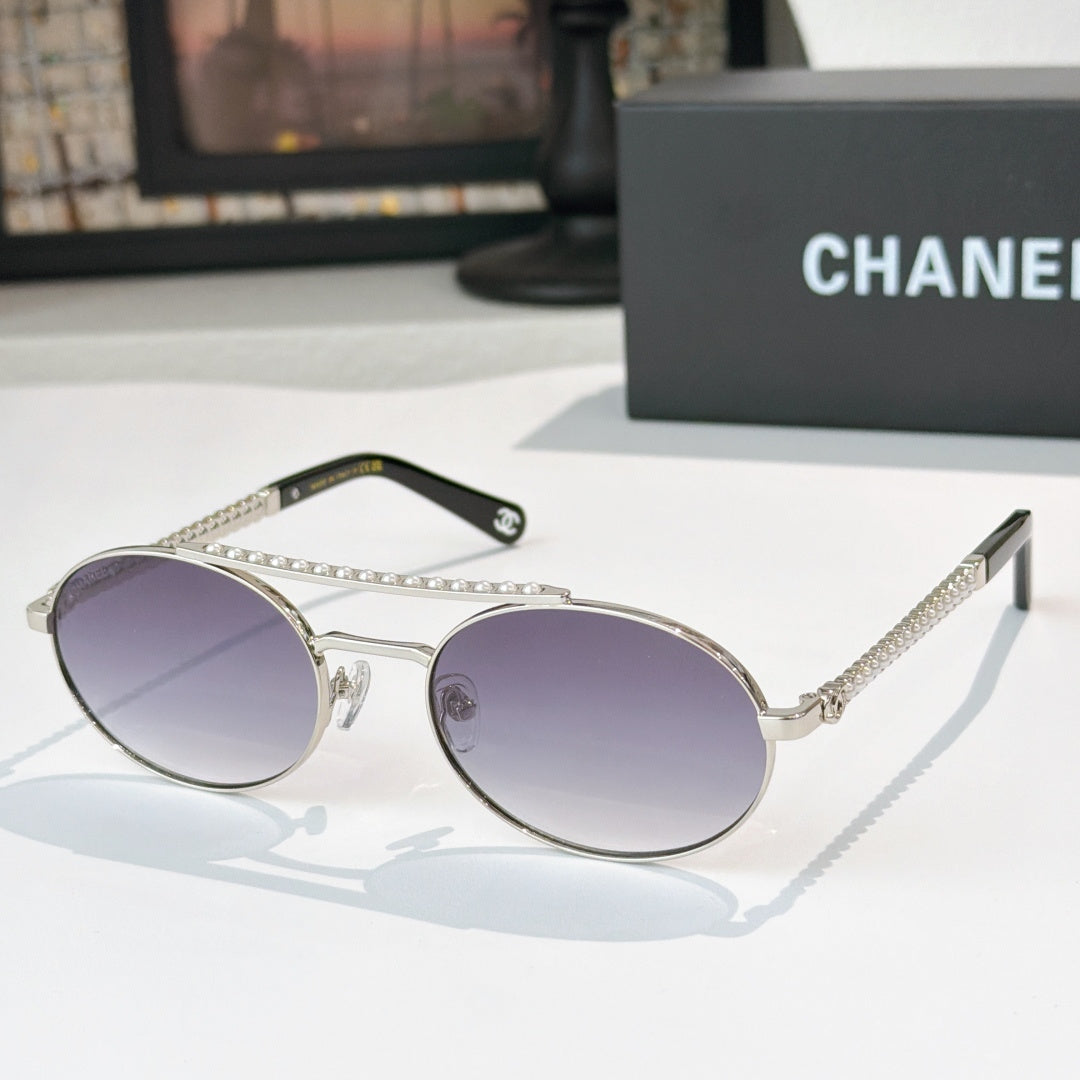 Silver-tone round sunglasses with purple tinted lenses and rhinestone chain temple detail