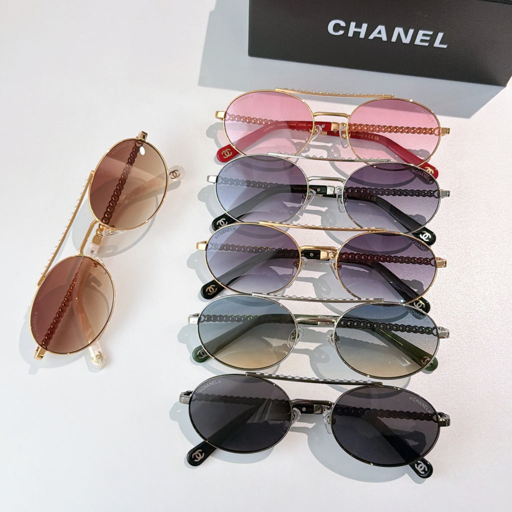 Stacked sunglasses with tinted lenses and chain accents, including pink and dark frames