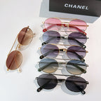 Stacked sunglasses with tinted lenses and chain accents, including pink and dark frames