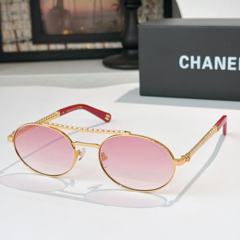 Gold-tone round sunglasses with pink tinted lenses and rhinestone chain accents