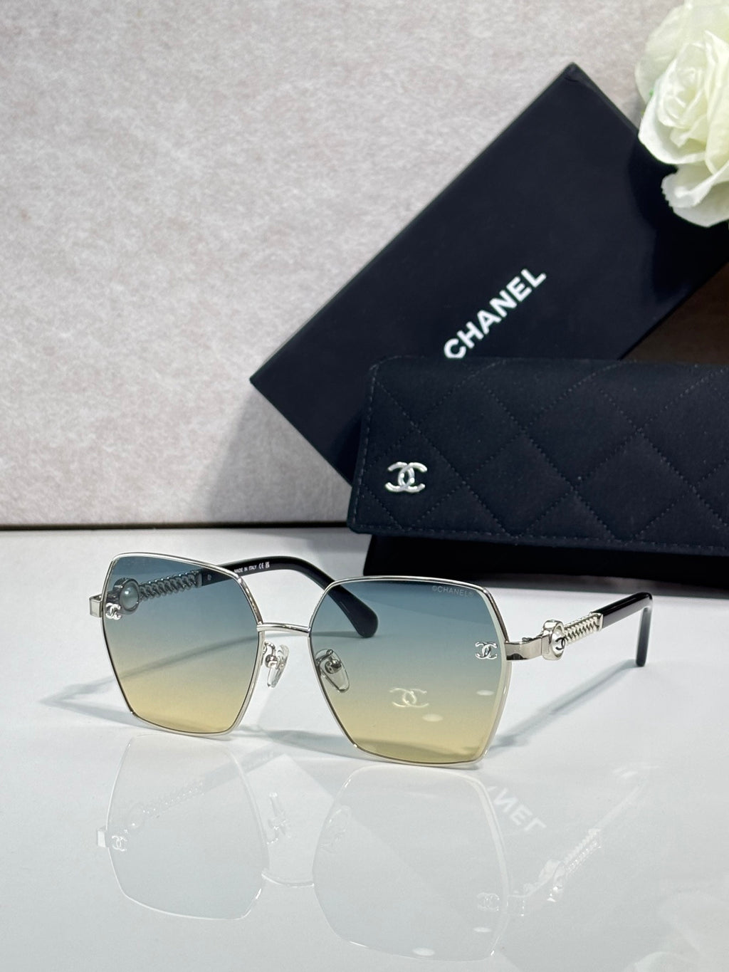 Square sunglasses with blue-to-yellow gradient lenses and gold-tone frames, with logo detail.