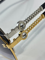 Close-up of metal chain bracelet-style detail and logo plaques on sunglasses frame arms.