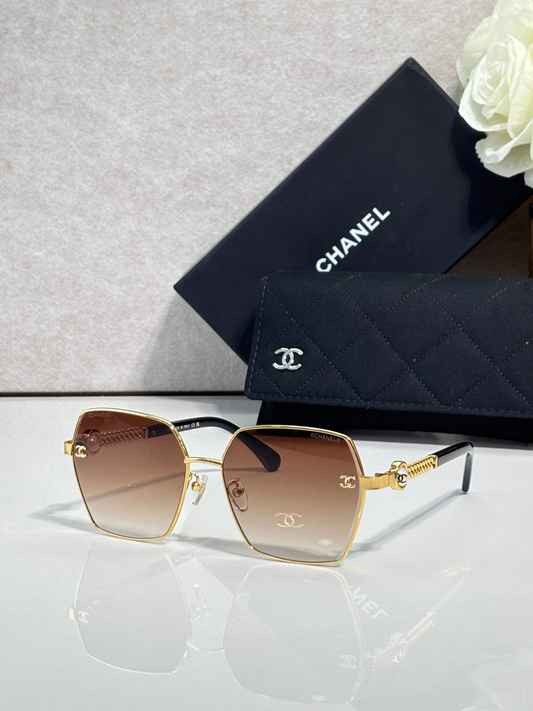Square sunglasses with rose gradient lenses and gold-tone frames, with logo detail on temples.