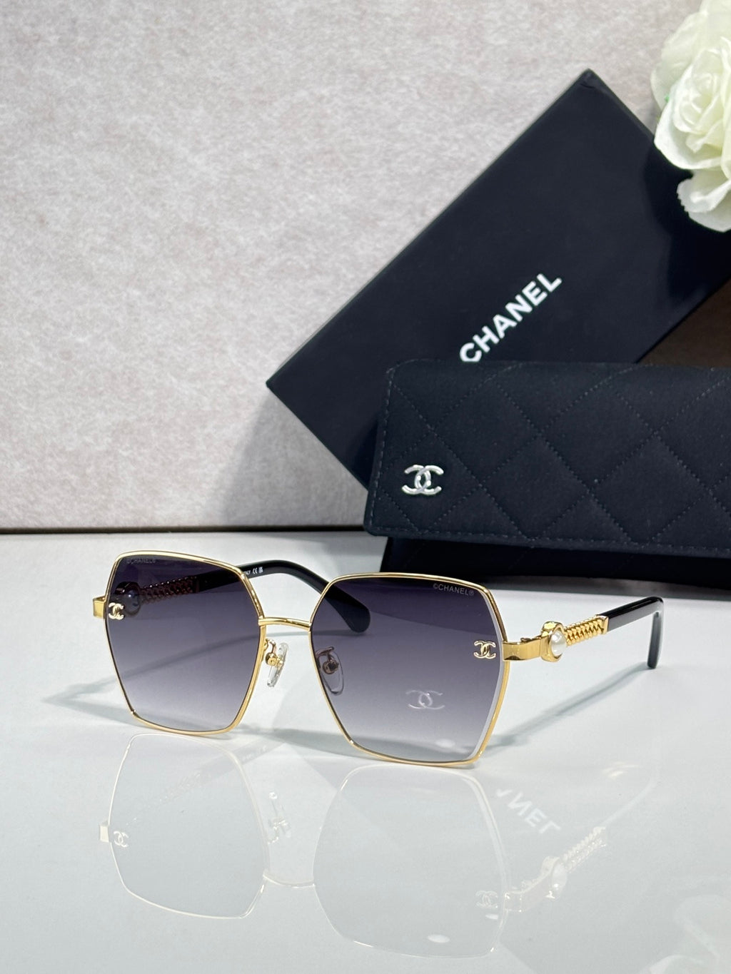 Chanel sunglasses with gold square frame and dark purple lenses, mirrored detail on arms