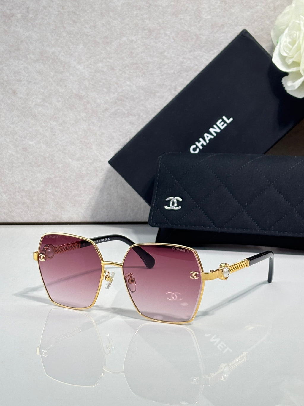 Square sunglasses with pink gradient lenses and gold-tone frames, with logo detail on temples.
