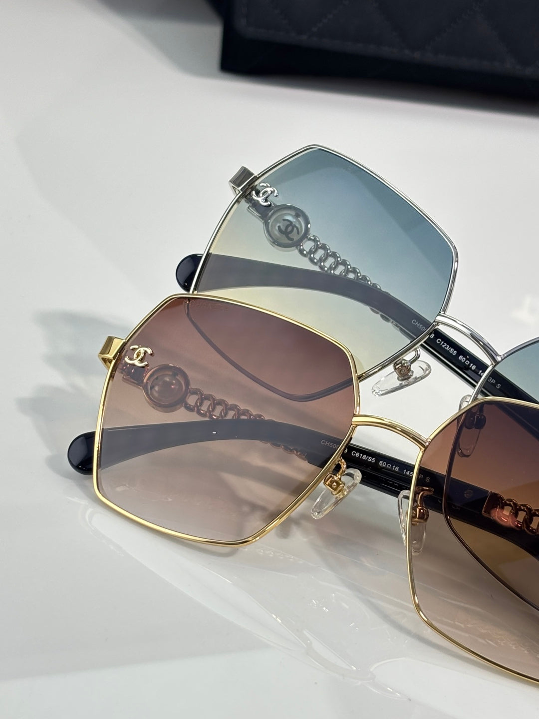Stacked square sunglasses with blue and brown gradient lenses in metal frames.