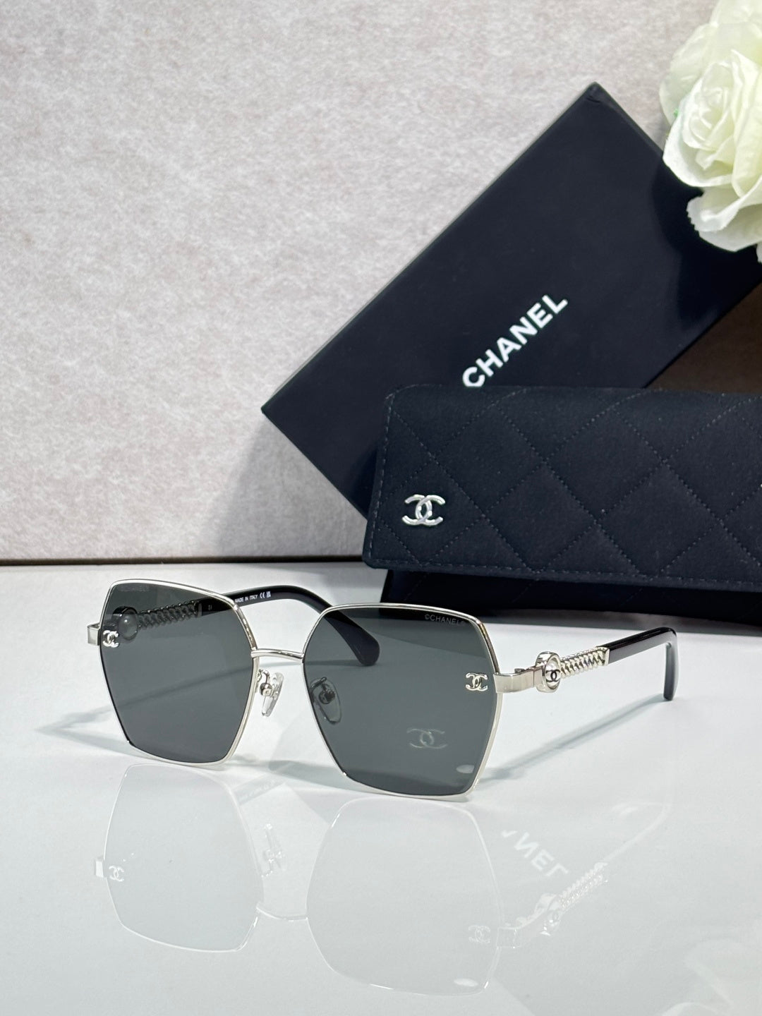 Square sunglasses with gray gradient lenses and silver-tone frames, with logo detail on temples.