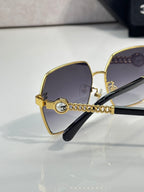 Chanel sunglasses angled view: gold square frame, dark gradient lenses, black temples