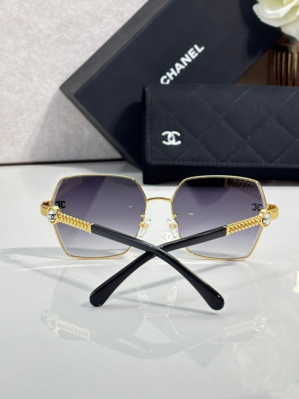 Chanel sunglasses front view: gold frames, dark gradient lenses, crossed black temples