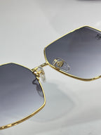 Gold-framed Chanel sunglasses close-up on lens and bridge with dark tinted lenses