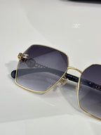 Chanel sunglasses pair at angle: dark square lenses, gold metal frame, black temples