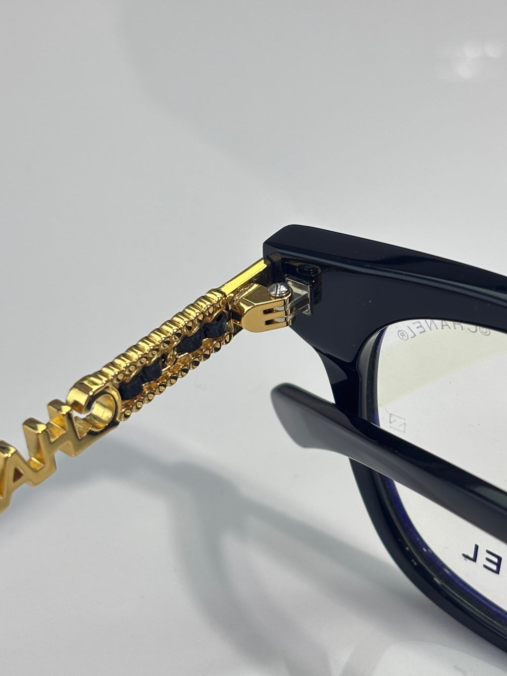 Black eyeglasses with gold chain temple detail
