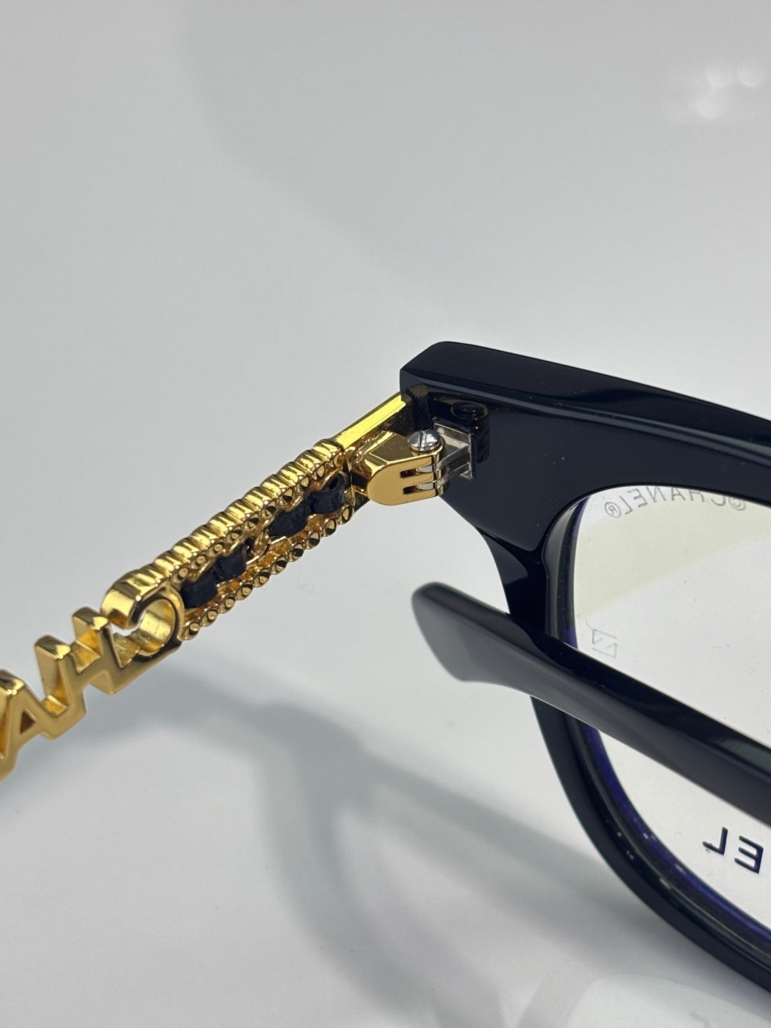 Black eyeglasses with gold chain temple detail