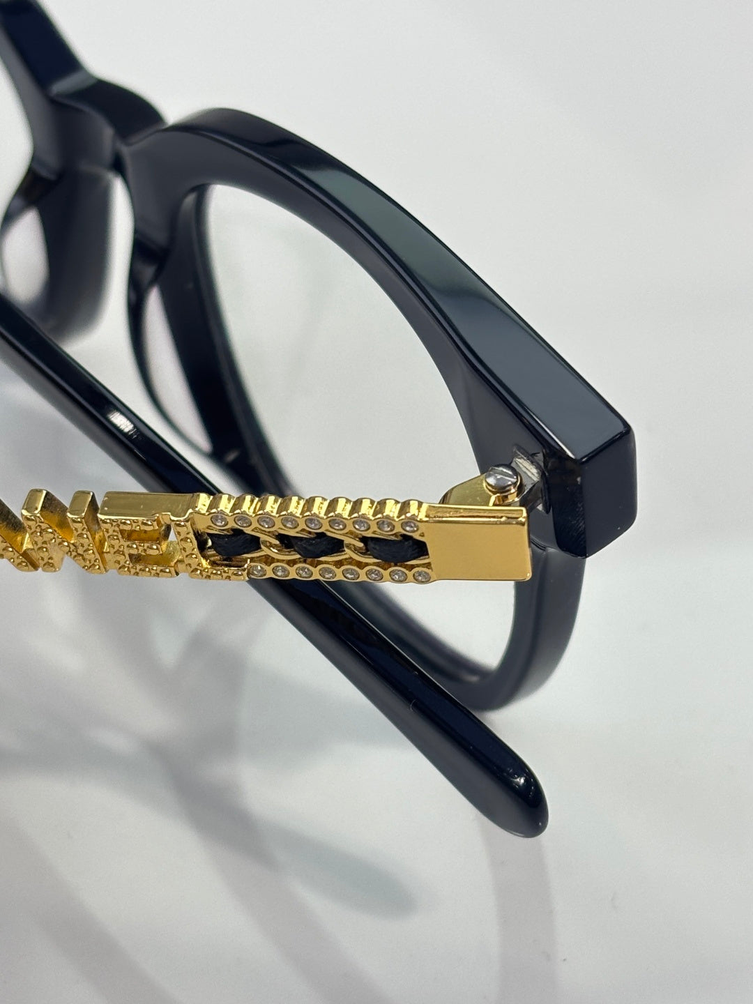 Black eyeglass side with gold chain bar accent