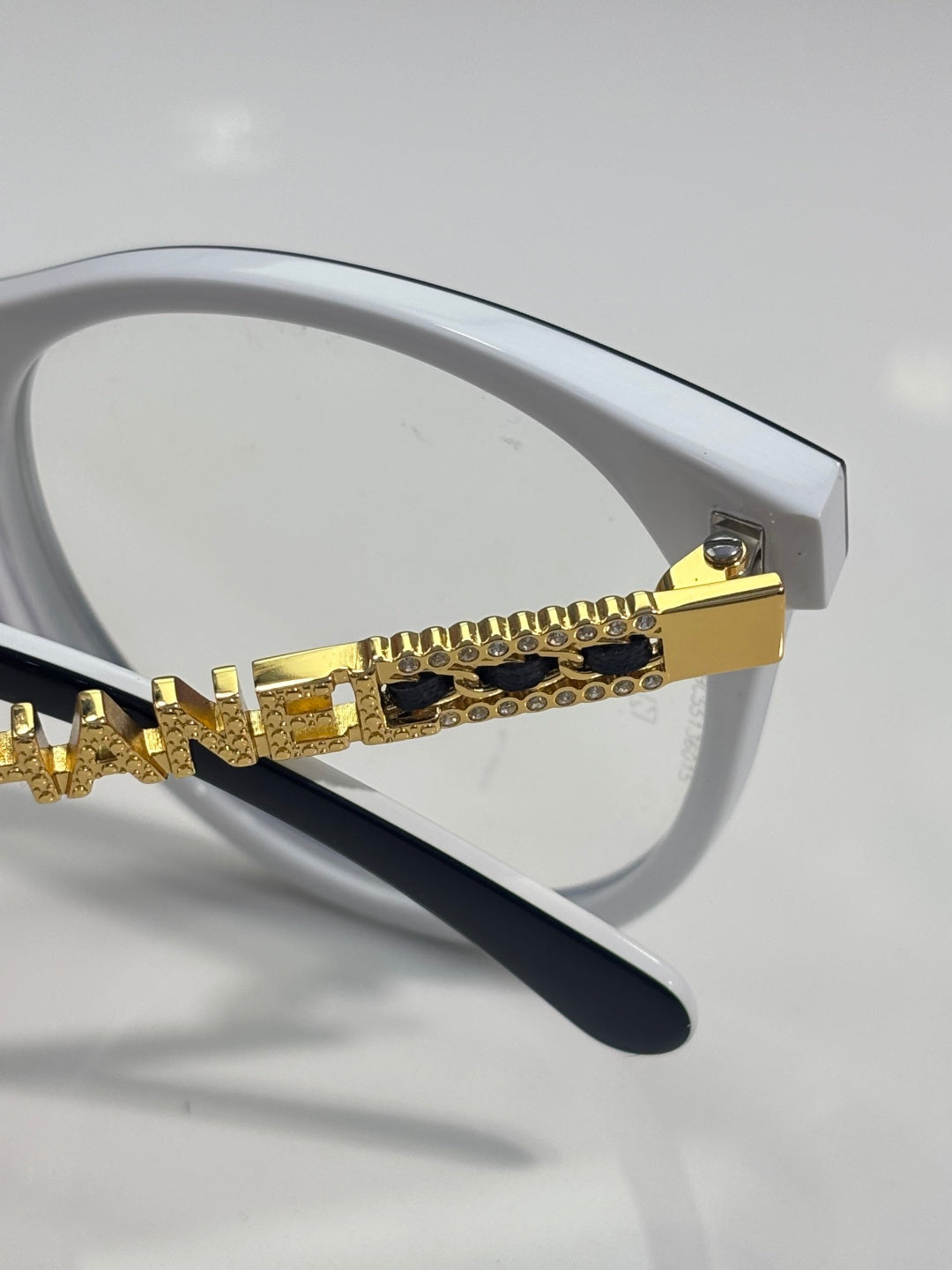 Chanel eyeglass frame with white arms and gold chain-style embellishment